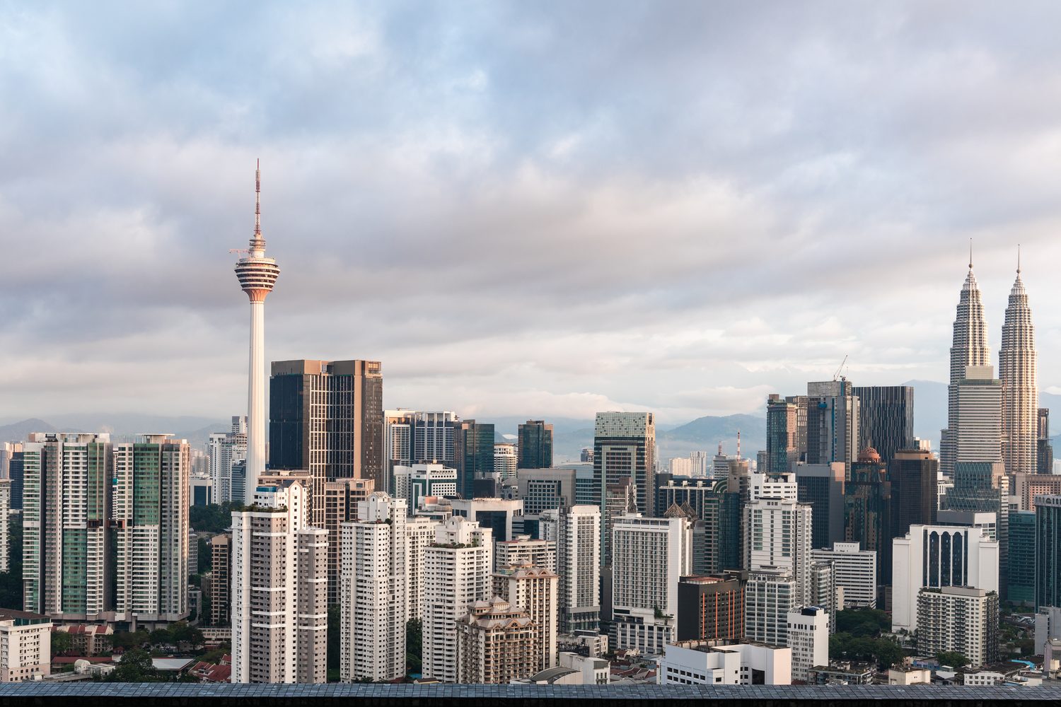 The Kuala Lumpur skyline under soft cloud, with the KL Tower and the Petronas Twin Towers