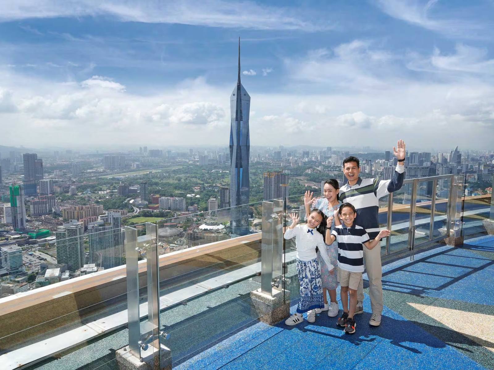 A Crestbrick group waving from a rooftop terrace high above Kuala Lumpur, with Merdeka 118 on the skyline