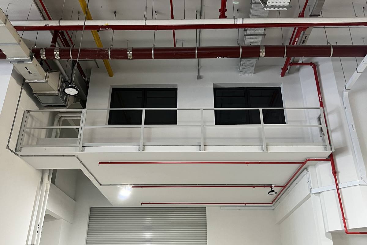 A vacant industrial unit with a high ceiling, exposed services and a roller shutter